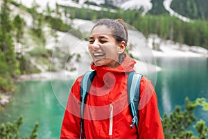 Portrait of delightful hiker woman with beautiful smile, mountains and lake around