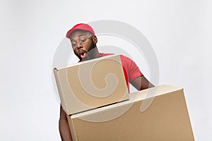 Portrait of delivery african american man in red shirt. he lifting heavy weight boxes against having a isolated on the