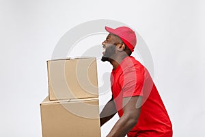 Portrait of delivery african american man in red shirt. he lifting heavy weight boxes against having a isolated on the
