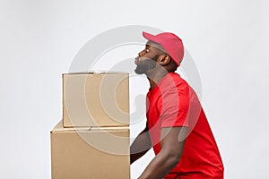 Portrait of delivery african american man in red shirt. he lifting heavy weight boxes against having a isolated on the