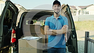 Portrait of delivery guy standing near commercial van with arms crossed smiling looking at camera