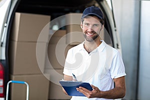 Portrait of delivery man holding a clipboard in front of van