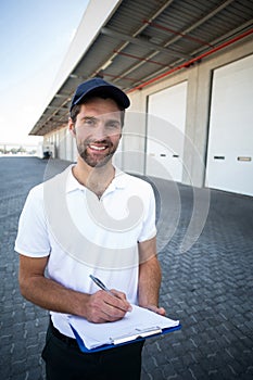 Portrait of delivery man is holding a clipboard and smiling to the camera