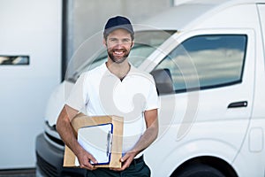 Portrait of delivery man holding parcels and clipboard