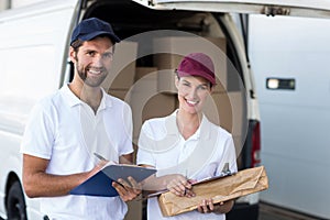 Portrait of delivery man and woman standing with clipboard and parcel