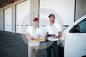 Portrait of delivery man and woman standing with clipboard and parcel