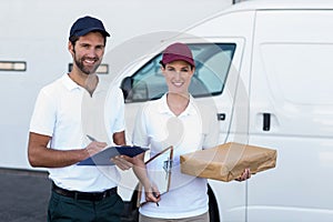 Portrait of delivery man and woman standing with clipboard and parcel