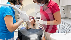 Portrait of dentist assistant holding salive ejector during teeth whitening procedure