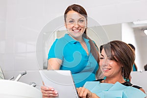 Portrait of a dentist discussing a treatment plan with a patient on a tablet