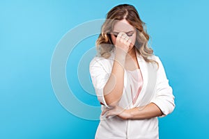 Portrait of depressed dramatic woman crying rubbing eyes, feeling desperate and hopeless. blue background