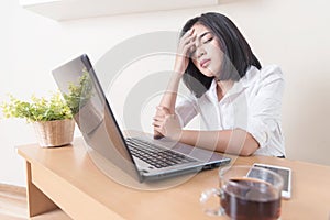 Portrait of depressed female entrepreneur sitting in front of the computer while working in the office. Young exhausted