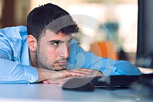 Portrait of a depressed office worker laying on his desk and thinking