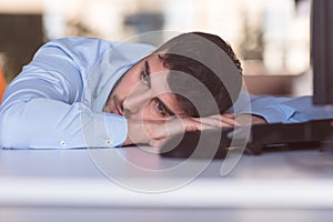 Portrait of a depressed office worker laying on his desk and thinking