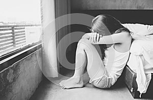 Portrait of depressed woman sitting alone on the floor in the bedroom.