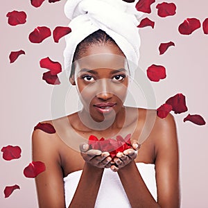 Portrait, dermatology and black woman with red petals, beauty and treatment on a white studio background. Face, African