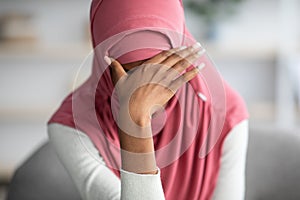 Portrait Of Desperate Black Muslim Woman In Hijab Sitting At Home