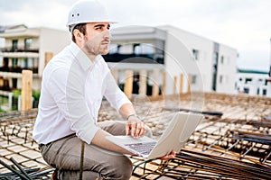 portrait, details of architect using laptop on building construction site