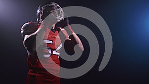 Portrait of determined professional American football player in helmet standing isolated. Confident man in uniform. Usa