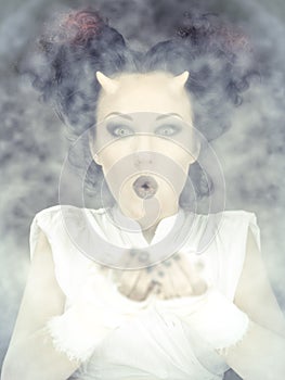 Portrait of devil woman blowing a white powder