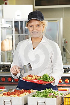 Portrait Of Dinner Lady Serving Meal In School Cafeteria