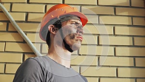 Portrait Dirty Building Worker on Background Brick Wall. Handsome Caucasian Serious Man in a Hard Hat. People Working Equipment