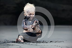 Portrait of dirty child on the black san beach
