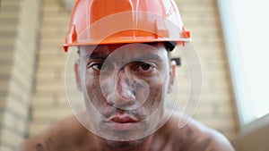 Portrait of a dirty construction worker in hard hat. Tired builder after work.