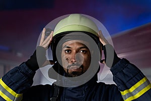 Portrait of dirty firefighter man on duty with fire truck in background at night, looking at camera.