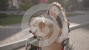 Portrait of disabled happy blind woman in wheelchair with her guide dog looking at camera. Asian handicapped visually