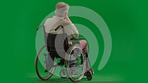 Portrait of disabled man isolated on chroma key green screen full shot. Senior bearded man sitting in wheelchair with