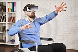 Portrait of a disabled man sitting in a wheelchair and using a VR headset