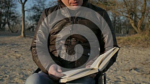 Portrait disabled person, handicapped reads bible, male invalid on wheel