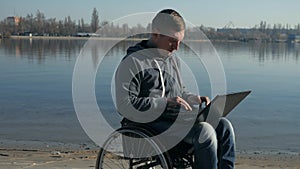 Portrait disabled person with laptop, on wheel chair leads video chat