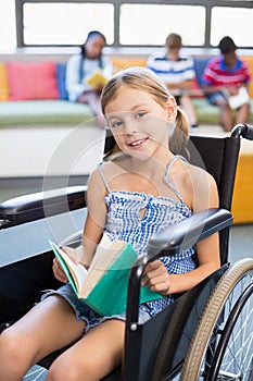 Portrait of disabled school girl reading book in library