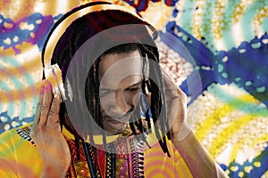 Portrait of a Disc Jockey (DJ) listening to reggae music, dreadlocks, audio headset, colored background, photo