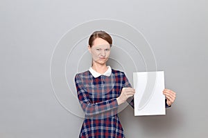 Portrait of disgruntled young woman holding white blank paper sheet
