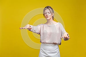 Portrait of disoriented blind young woman with fair hair in casual beige blouse, isolated on yellow background photo
