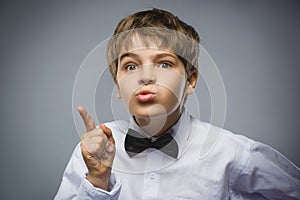 Portrait of displeased angry boy with threatens finger isolated on gray background. Negative human emotion, facial