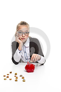 Portrait of Displeased Caucasian Teenager Girl in Dark Jacket Putting Coin Into The Piggybank For Savings