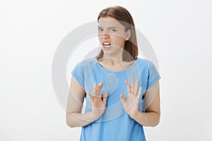 Portrait of displeased and disgusted european woman in blue t-shirt, shaking palms in rejection gesture, disliking idea