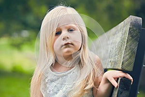 Portrait of displeased little girl sitting on bench