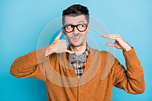 Portrait of displeased man look empty space grinning show fingers call symbol isolated on blue color background