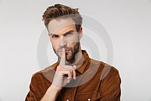 Portrait of displeased young man gesturing silence sign