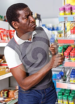 Portrait of disquieted African man choosing spice in supermarket