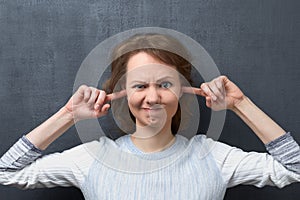 Portrait of dissatisfied girl covering ears with hands