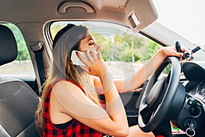 Young beautiful reckless woman using smartphone while driving car photo