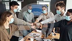 Portrait of diverse business people in masks giving fist bump
