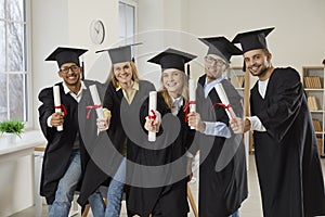 Portrait of diverse graduates with diplomas certificates