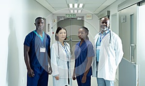 Portrait of diverse group of four doctors and healthcare workers in hospital corridor