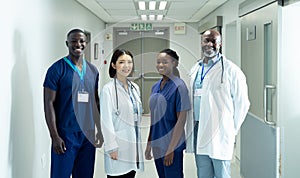 Portrait of diverse group of four doctors and healthcare workers smiling in hospital corridor
